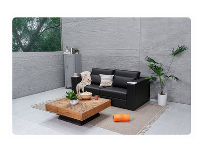 Black vegan leather Rezy Smart Sofa on a rug in a minimalist concrete-walled living space with plants